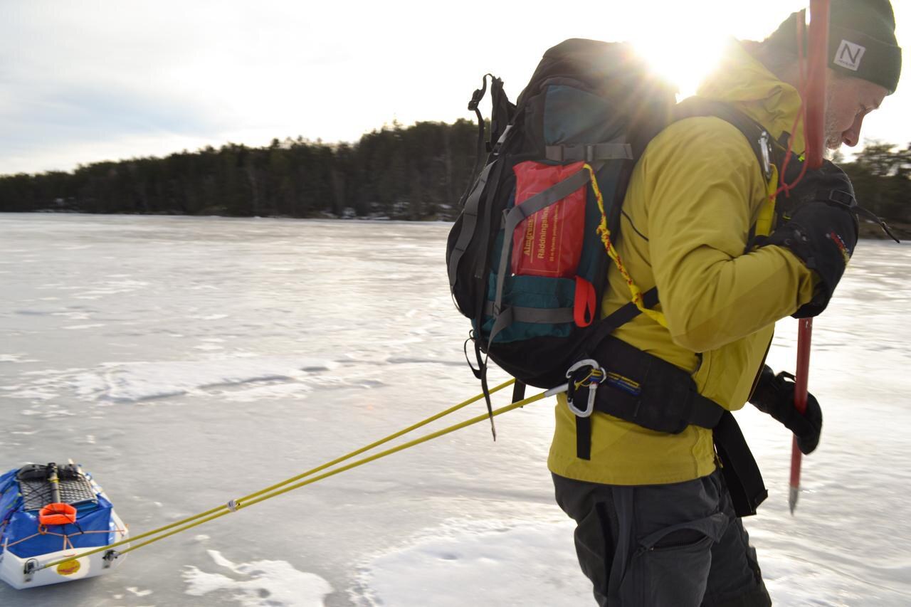 Skier pulling a KARG pulk across a winter landscape